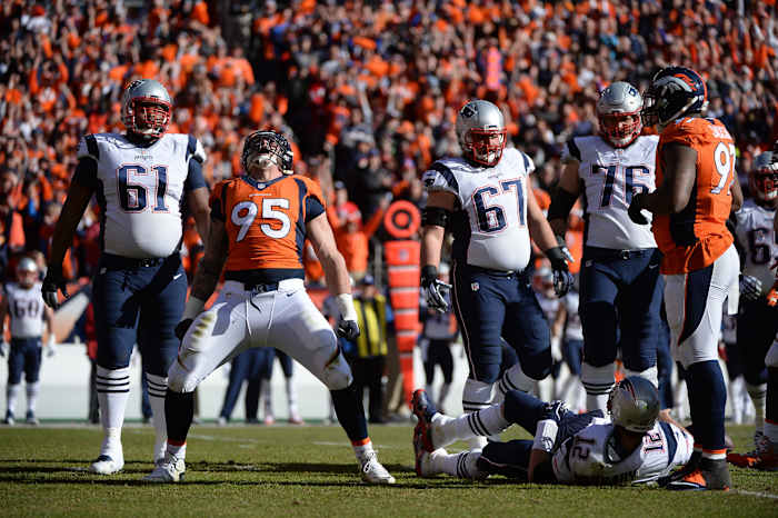 Derek Wolfe celebrates on the field; nearby Tom Brady lies on his back.